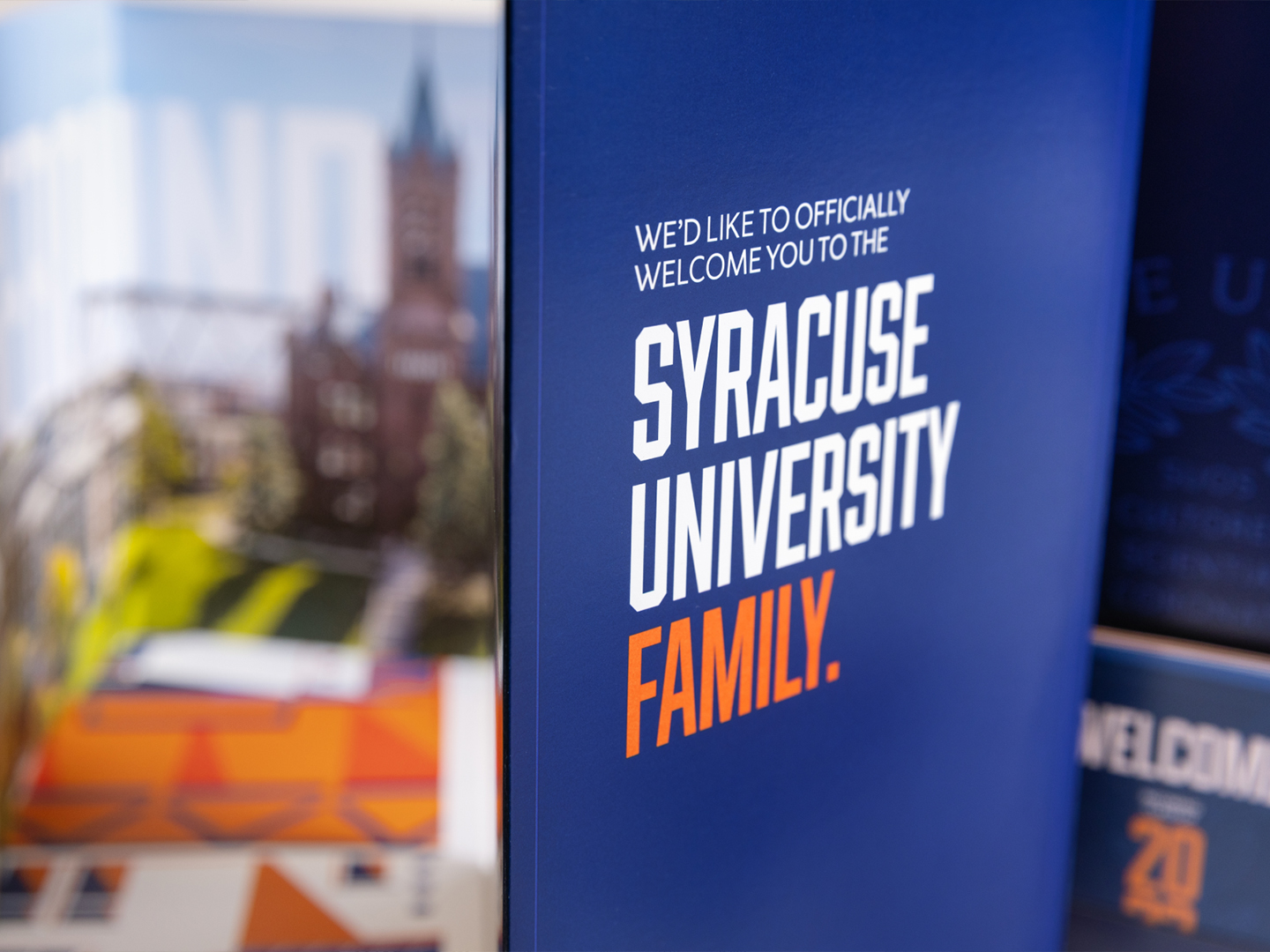 Close-up of a print design piece, with the words 'We'd like to officially welcome you to the Syracuse University family' visible.